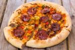 Delicious Baked Salami Pizza Served On Rustic Wooden Table Stock Photo