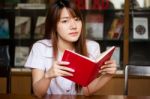 Portrait Of Thai Adult Student University Uniform Beautiful Girl Reading Red Book Stock Photo