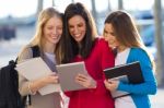 Students Having Fun With Smartphones And Tablets After Class Stock Photo