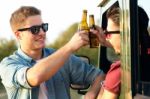 Portrait Of Two Friends Toasting With Bottles Of Beer In Car Stock Photo