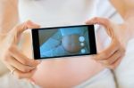 Pregnant Woman Taking A Photo Of Her Belly Stock Photo