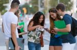 A Group Of Students Having Fun With Smartphones After Class Stock Photo