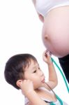 Little Asian Boy Examining Pregnant Mother's Tummy Stock Photo