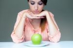 Upset Brunette Woman With Green Apple On A Plate Stock Photo