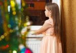 Little Girl Standing At The Window At Christmas Stock Photo