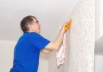 Man Smoothes The Wallpaper With A Spatula Stock Photo