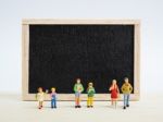 Miniature Children Standing In Front Of A Blackboard On Wooden B Stock Photo