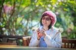 Portrait Of 40s Years Asian Woman With Cool Juicy Drinking Bottle In Hand With Happiness Emotion Sitting In Beautiful Park Background Stock Photo