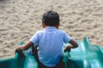 A Young Boy Sliding Down A Playground Slide Stock Photo