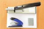 Big And Small Staplers With Staples And Paper On The Table Stock Photo