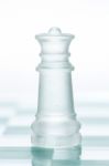 Glass Chess Queen Is Standing On Board, Cut Out From White Backg Stock Photo