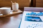 Coffee Cup  On A Table With Laptob And Graph Finance Diagram In Stock Photo