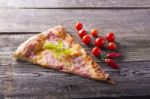 Pizza Cut On Wooden Table, Cherry Tomato And Hot Peppers Stock Photo