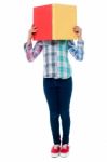 School Girl Hiding Her Face Behind A Notebook Stock Photo