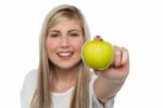 Smiling Girl Displaying Fresh Green Apple To The Camera Stock Photo