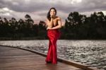 Beautiful Young Woman In The Gardens Wearing A Long Silk Red Dress Stock Photo