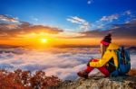 Young Woman Sitting On The Hill Of High Mountains At Sunrise Stock Photo