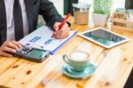 Business Man Sitting On A Calculator To Figure Out In A Coffee S Stock Photo