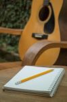 Yellow Acoustic Guitar On Wooden Table Stock Photo