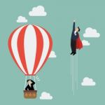 Businessman Superhero Fly Pass Businessman In Hot Air Balloon Stock Photo