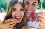 Young Couple Eating Grapes On Romantic Picnic In Countryside Stock Photo