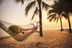 Woman Lying In Beach Cradle And Taking A Photograph By Smart Phone Stock Photo