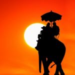 Silhouette Elephant With Tourist At Sunset Stock Photo
