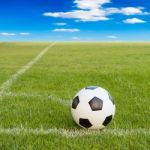 Soccer Ball On Soccer Field Against Blue Sky Stock Photo