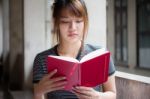 Portrait Of Thai Adult Beautiful Girl Reading Red Book Stock Photo