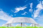 Solar Panels On Green Grass Field Against Blue Sky Background Stock Photo