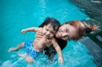 The Kid And Mom Play Together In The Pool Stock Photo