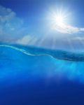 Under Blue Water With Sun Shining Above Stock Photo