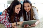 Two Beautiful Young Woman Friends Using Digital Tablet At Home Stock Photo