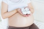 Pregnant Belly With A Pair Of White Shoes Stock Photo