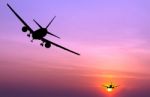 Silhouetted Commercial Airplane Flying At Sunset Stock Photo