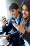 Young Couple Using Mobile Phone In Cafe Stock Photo