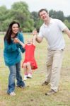 Lovely Couples Playing With Their Happy Daughter At The Park Stock Photo