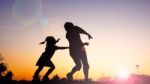 Silhouette Happy Family Mother And Daughter In The Park At Sunset Stock Photo