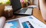 Coffee Cup  On A Table With Laptob And Graph Finance Diagram In Stock Photo