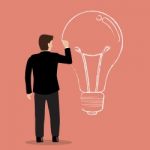 Businessman Drawing Lightbulb On Wall Stock Photo