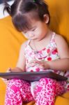 Little Asian Girl Using Digital Tablet, Child Finger Point At Co Stock Photo