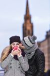 Young Couple In Love Embracing And Drinking Hot Drink From Red C Stock Photo