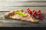 Piece Cut Of Pizza On Table, Cherry Tomato And Hot Peppers Stock Photo