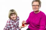 Grandmother Putting Euro Coin In Grandchild's Piggy Bank Stock Photo