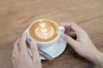 Hand On Hot Cup Of Coffee Latte Stock Photo