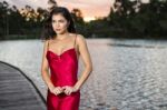 Beautiful Young Woman In The Gardens Wearing A Long Silk Red Dress Stock Photo