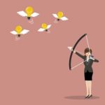 Business Woman With A Bow And Arrow Hitting The Light Bulb Fly Stock Photo