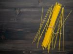 The Thin Spaghetti On Black Wooden Background. Yellow Italian Pa Stock Photo