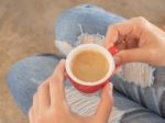 Woman In Torn Jeans Sitting At Coffee Shop Stock Photo