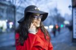 Lady In Red Coat With Smartphone In Hands Going Through The City Stock Photo